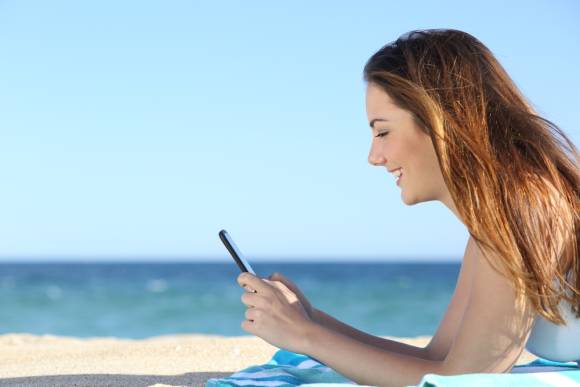 Frau mit Smartphone am Strand 
