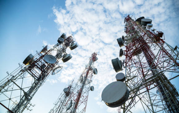 Mobilfunkmasten vor blauem Himmel mit Woken 