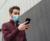 Mann mit Atemschutzmaske und Smartphone