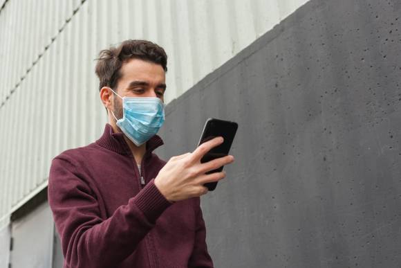 Mann mit Atemschutzmaske und Smartphone 