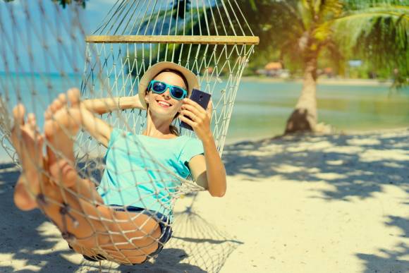 Urlauber mit Smartphone in Hängematte 