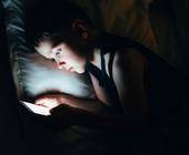 Junge benutzt in der Nacht sein Smartphone