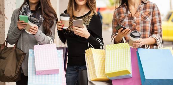 Junge Frauen mit Einkaufstüten und Smartphones 
