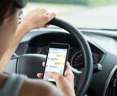 Frau am Steuer mit Smartphone