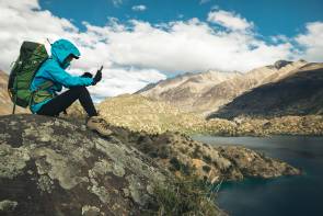 Mann mit Smartphone im Gebirge 