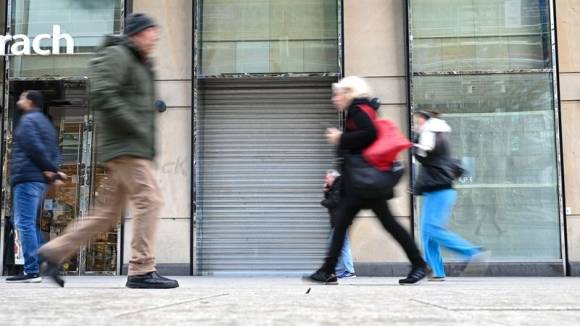 Passanten gehen auf der Einkaufsmeile Zeil in Frankfurt/Main an einem leerstehenden Geschäft vorbei 