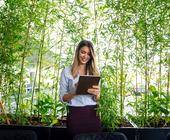 Frau mit Tablet steht vor Pflanzen
