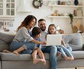 Familie sitzt auf dem Sofa und surft im Internet