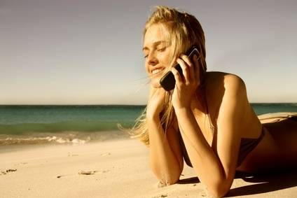 Junge Frau am Strand beim Telefonieren 