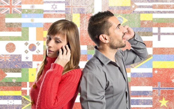 Frau und Mann telefonieren mit einem Smartphone vor einer Wand mit Landesflaggen