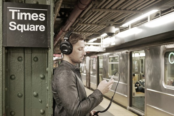 Mann steht mit Kopfhörer auf dem Kopf in einer Ubahnhaltestelle 