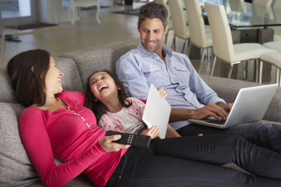 Familie sitzt auf der Couch mit mobilen Geräten 