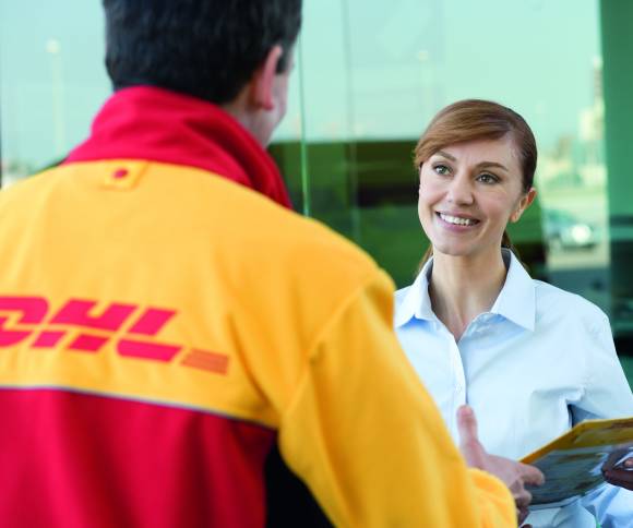 DHL-Bote übergibt Fau Paket an der Haustür 