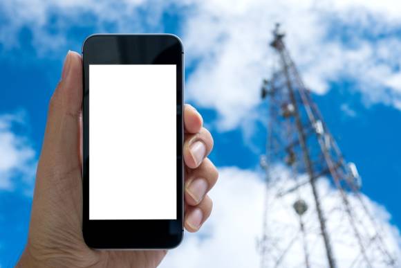 Smartphone mit Antennenmast im Hintergrund 