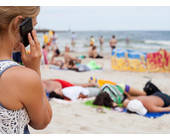 Frau am Strand mit Smartphone