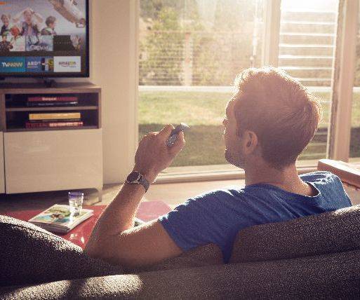 Mann sitzt auf dem Sofa vor dem Fernseher 