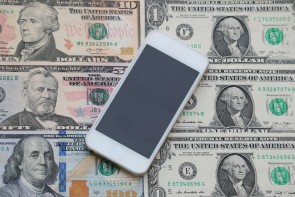 Smartphone liegt auf Dollar-Noten 